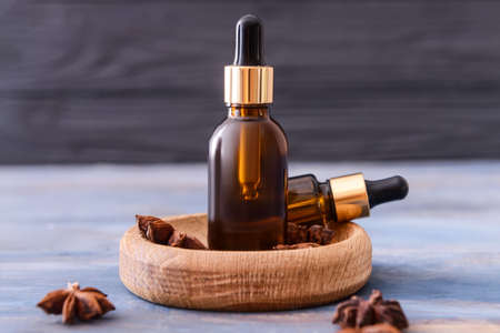 Bottles of anise essential oil on color wooden background