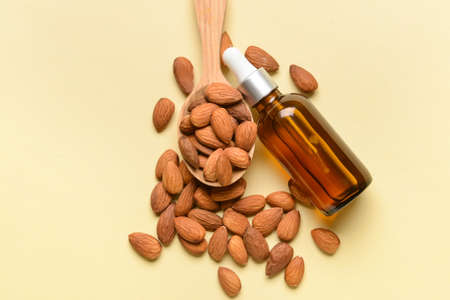 Bottle of almond essential oil on color backgroundの写真素材