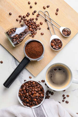 Composition with cup of coffee, beans and powder on light background