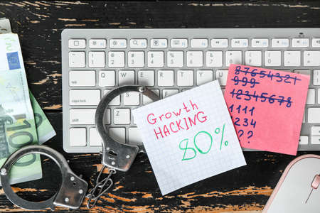 Composition with PC keyboard, money and handcuffs on wooden background. Hacking concept