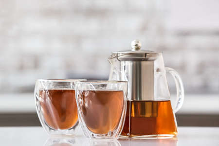 Teapot and glasses with hot tea on table in kitchenの写真素材