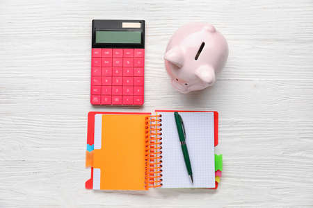 Calculator with notebook and piggy bank on white wooden backgroundの写真素材