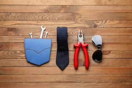 Set of tools, necktie and glasses on wooden background