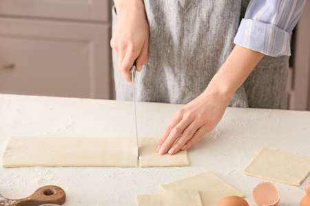 Woman cutting dough on kitchen table