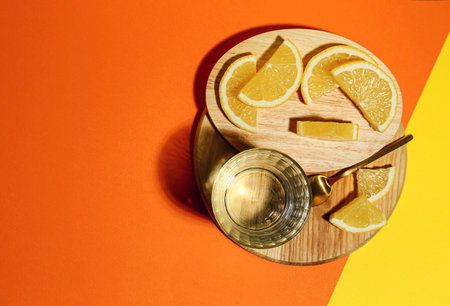 Board with lemons and glass of water on color backgroundの写真素材