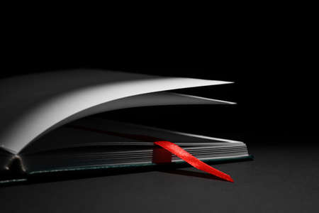 Open book with bookmark on dark background, closeupの写真素材