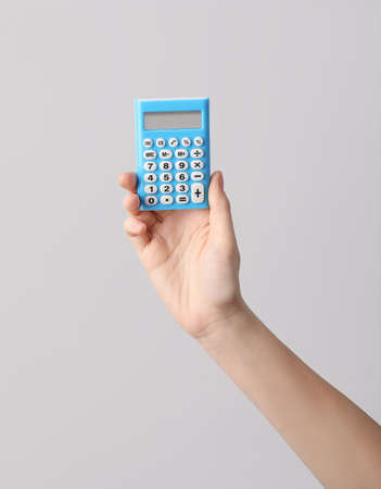 Woman with calculator on light backgroundの写真素材