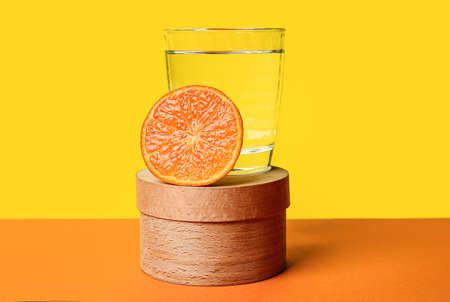Wooden box, orange and glass of water on color backgroundの写真素材