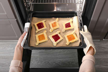 Woman putting baking tray with uncooked Danish pastry into ovenの写真素材