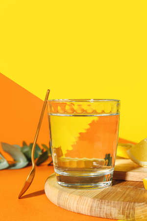 Board with lemons and glass of water on color backgroundの写真素材
