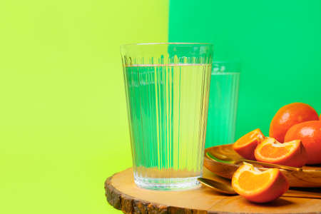 Board with oranges and glasses of water on color backgroundの写真素材