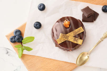 Board with tasty cocoa cake on table