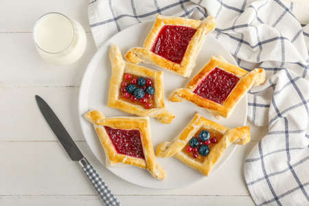 Plate with danish pastry on white wooden background