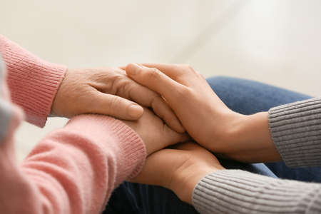 Young woman holding hands of grandmother at homeの写真素材