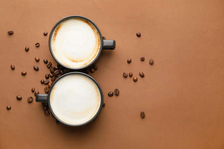Cups of hot cappuccino coffee on color backgroundの写真素材
