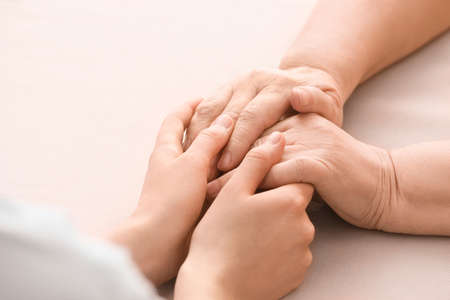 Young woman holding hands of grandmother at tableの写真素材