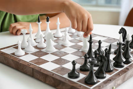 Cute African-American boy playing chess at home, closeup