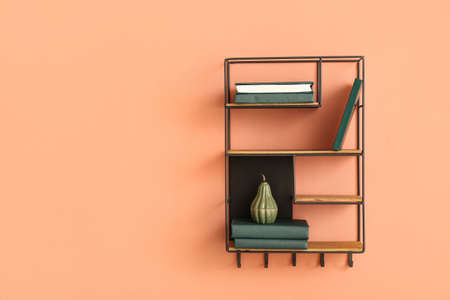 Modern shelf with books and decor on color wallの写真素材