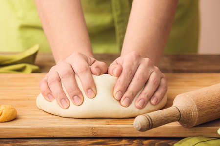 Woman kneading dough on wooden boardの写真素材