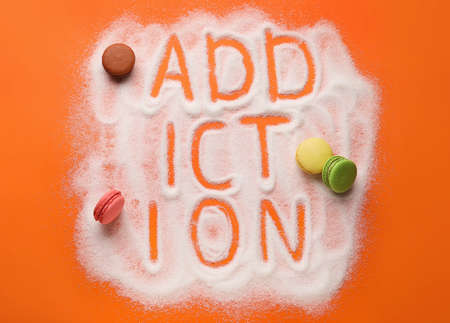 Word ADDICTION, cakes and sweet sugar on color backgroundの写真素材