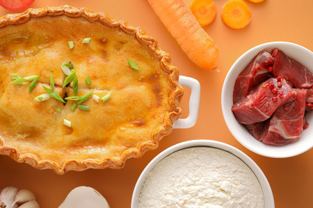Tasty beef pot pie with ingredients on color background