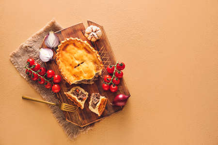 Board with tasty beef pot pie on color background
