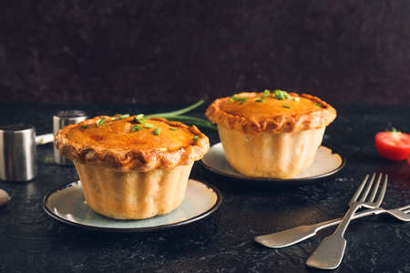 Tasty beef pot pies on dark background