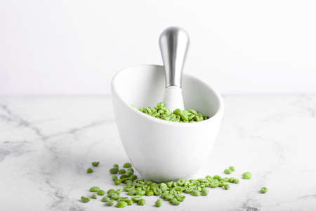 Mortar and pestle with green coffee beans on light backgroundの写真素材