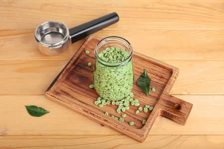 Jar with green coffee beans on wooden background