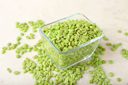 Bowl with green coffee beans on light backgroundの写真素材