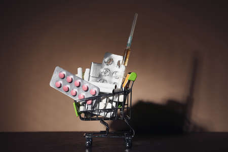 Shopping cart with drugs and cigarettes on dark background. Concept of addictionの写真素材
