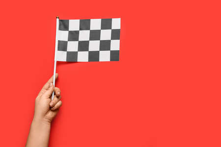 Female hand with racing flag on color backgroundの写真素材
