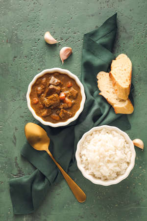 Bowls with tasty beef curry and rice on color backgroundの写真素材