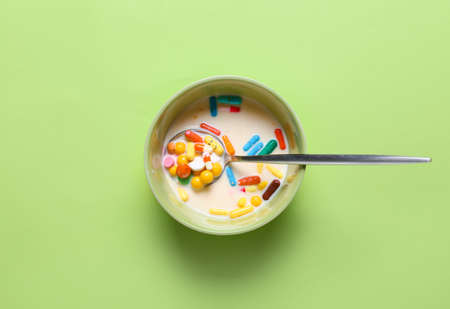 Bowl with pills and milk on color background. Concept of addictionの写真素材