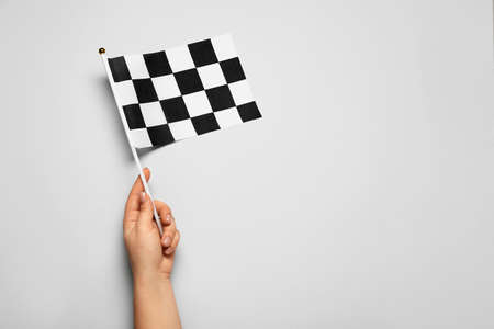 Female hand with racing flag on light background
