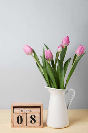 Calendar and vase with flowers on table. International Women's Day celebration
