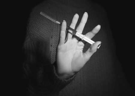 Woman with syringe on dark background. Concept of addiction to drugsの写真素材