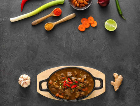Dish with tasty beef curry and ingredients on dark backgroundの写真素材