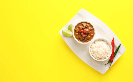 Bowls with tasty beef curry and rice on color backgroundの写真素材