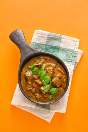 Frying pan with tasty beef curry on color backgroundの写真素材