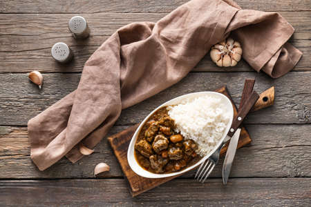 Plate with tasty beef curry and rice on wooden backgroundの写真素材