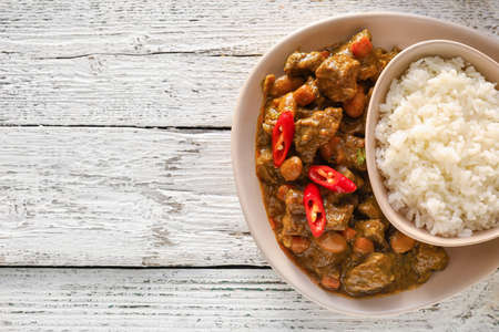 Plate with tasty beef curry and rice on white wooden backgroundの写真素材