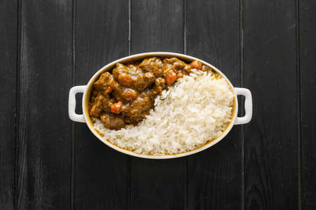 Dish with tasty beef curry on dark wooden backgroundの写真素材