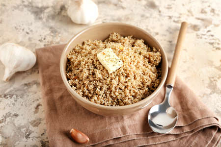 Bowl with tasty quinoa, butter and garlic on grunge background