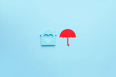 House figure with umbrella on color background. Property insurance conceptの写真素材