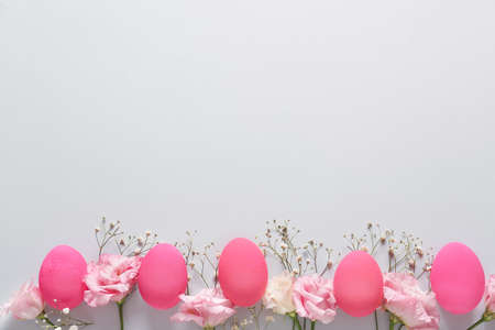 Beautiful Easter eggs and flowers on light background