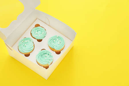 Box with tasty cupcakes on color backgroundの写真素材