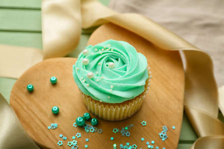 Composition with tasty cupcake on color wooden background, closeupの写真素材