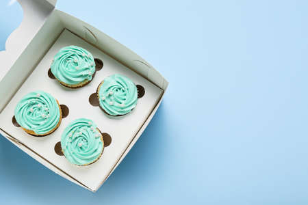 Box with tasty cupcakes on color backgroundの写真素材