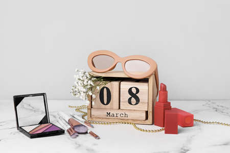Calendar with makeup cosmetics on light background. International Women's Day celebration